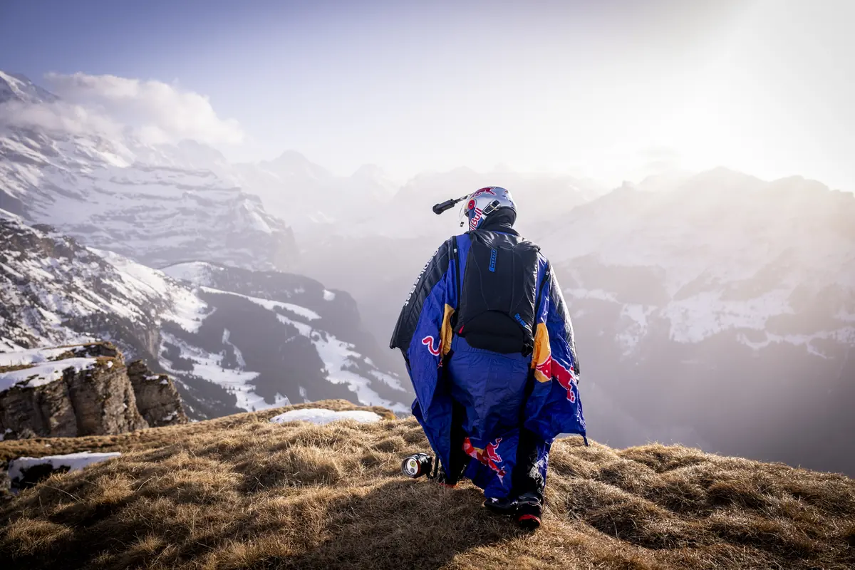 Basejumper im Wingsuit auf einem Bergkamm über dem Tal