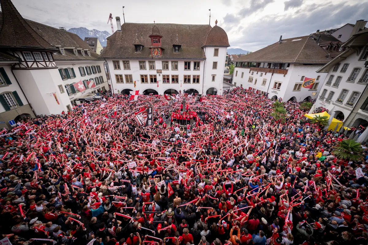 Dicht gedrängte Menschenmenge in Rot und Weiss auf einem Stadtplatz